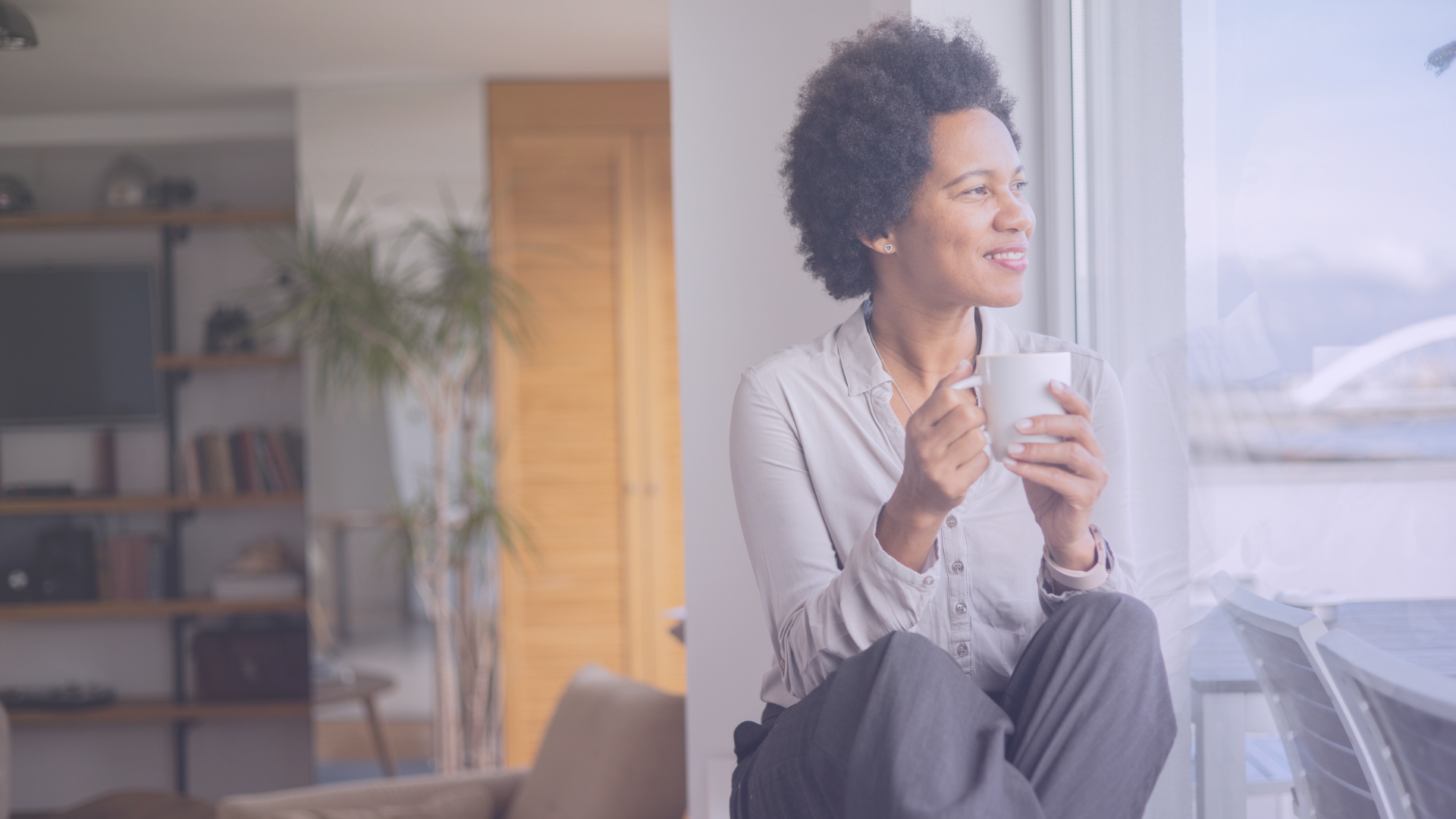 Women sitting and holding a cup of coffee while staring contently out the window