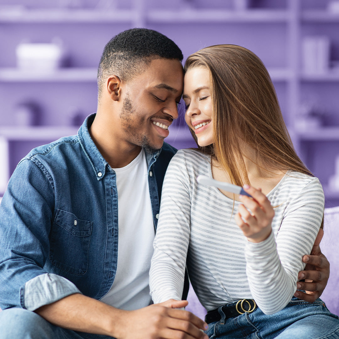 Young couple smiles over a Proov pregnancy test.