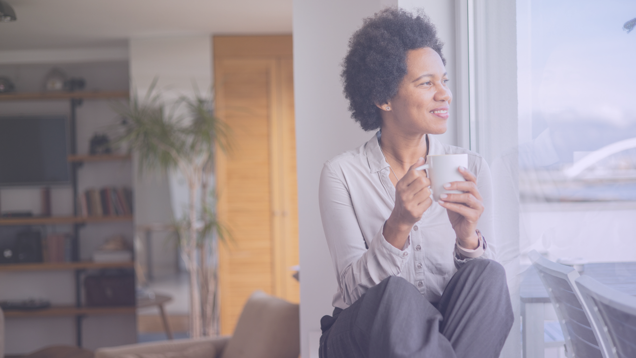 Women sitting and holding a cup of coffee while staring contently out the window